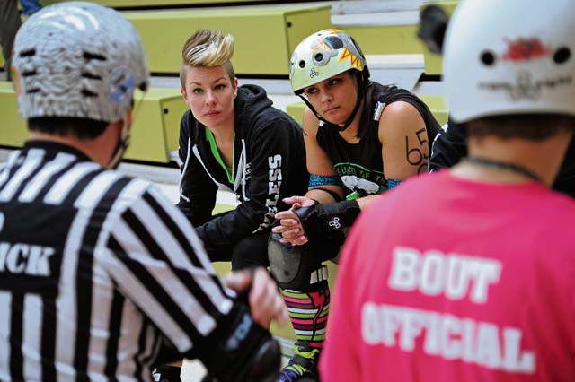 Team members listen to the bout official for rules and restrictions.