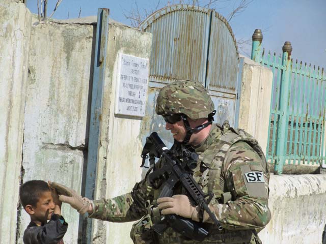 U.S. Air Force photo Chief Master Sgt. Jason Paker, 455th Expeditionary Security Forces Group superintendent, high-fives a child while performing security operations recently in Parwan Province near Bagram Airfield in Afghanistan.