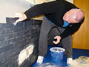 Courtesy photo Senior Master Sgt. Rich Rizzo, 521st Air Mobility Operations Wing air transportation superintendent, places bricks along the wall of the 521st AMOW heritage room at the Kisling NCO Academy on Kapaun. The heritage room was completed Feb. 15 by four volunteers from the 521st AMOW who had a commitment to their wing heritage and professional development.