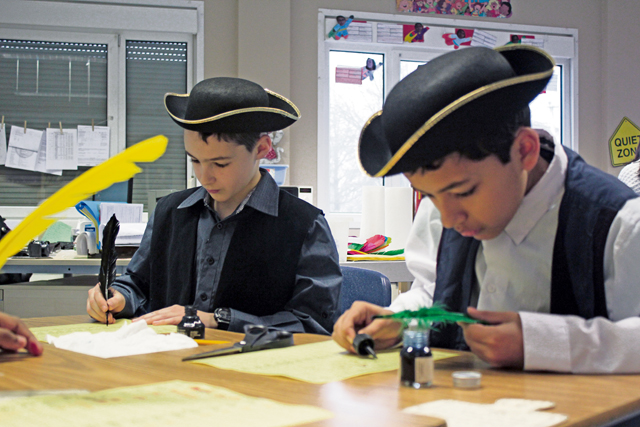 Courtesy photo Fifth-graders at Landstuhl Elementary Middle School held a Colonial Days Celebration to culminate their study of this historical period.  Students were involved in activities such as churning butter, cross stitching, candle making, dancing, cooking, and more. In this photo, Jakob Thorpe (left) and Christopher Teferi (right) are busy quilling and crossing.