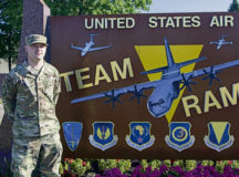 U.S. Air Force Staff Sgt. Corey Drake, 1st Combat Communications client systems technician, stands in front of a wing sign at Ramstein Air Base, Aug. 5. Drake saved a two-year-old girl from drowning at a popular lake in southwest Germany, Aug. 2.