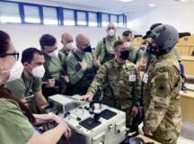 U.S. Air Force Staff Sgt. Jacob Wade, 52nd Operations Support Squadron non-commissioned officer in charge of aircrew flight equipment quality assurance, center right, demonstrates the use of a joint combined aircrew system tester training system at the 21st tactical air base in April 2021. JCASTs are used to equip aircrew with the right amount of oxygen needed to keep flying in the event of high altitudes. (Courtesy Photo)