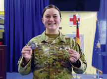 U.S. Air Force Senior Airman Audrey Allen, 86th Aeromedical Evacuation Squadron aeromedical evacuation technician and flight instructor, holds up the coins she received for being nominated Airlifter of the Week at Ramstein Air Base, Germany, Aug. 5, 2021. Allen earned two coins from Col. Denny Davies, 86th Airlift Wing vice commander, and 86th AW Command Chief Master Sgt. Hope Skibitsky for streamlining the training pipeline for incoming Airmen and helping them complete upgrade training faster. (U.S. Air Force photo by Airman 1st Class Madelyn Keech)