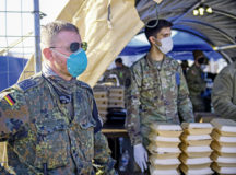 A German service member stands at the food tent with volunteer U.S. Airmen prior to serving lunch to evacuees at Ramstein Air Base, Germany, Sept. 5, 2021. The arrival of the German military came in response to a limited number of U.S. military members being capable of supporting due to tremendous demand and normal mission operations remaining unchanged. (U.S. Air Force photo by Senior Airman Kiaundra Miller)